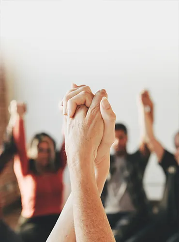 Terapia-familiar-s Sesión de terapia grupal donde participantes levantan las manos en señal de unión y apoyo emocional